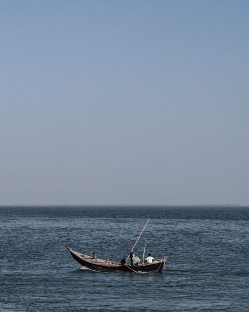 Free A small fishing boat with two fishermen on a calm day in Karachi's Arabian Sea. Stock Photo