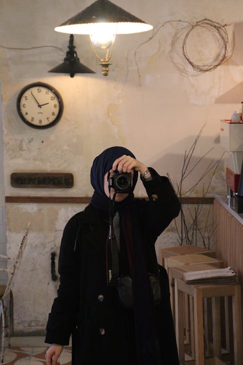 Portrait of Woman in Black Coat and Hijab Taking Pictures with Camera