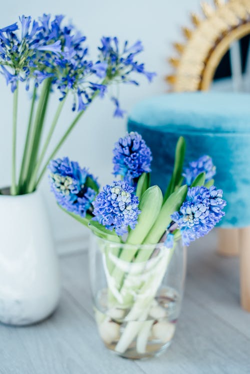 Blue flowers in a vase on a table next to a blue chair
