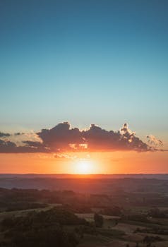 A stunning sunset with dramatic clouds over a scenic landscape, captured from above.