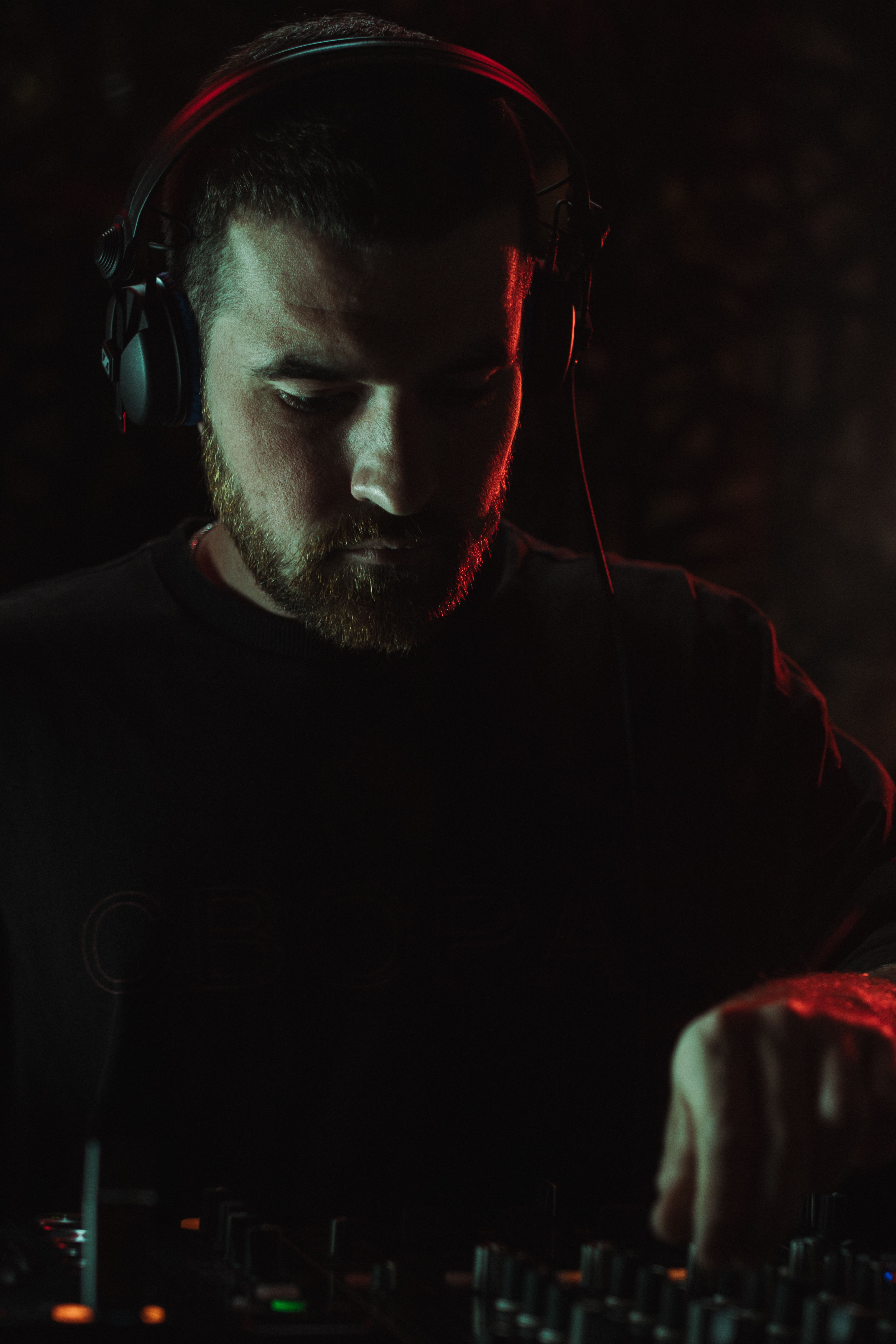 Free Focused DJ mixing music on a sound console in a dark club atmosphere. Stock Photo