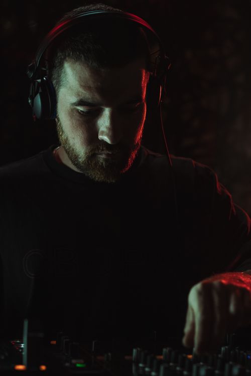 Free Focused DJ mixing music on a sound console in a dark club atmosphere. Stock Photo