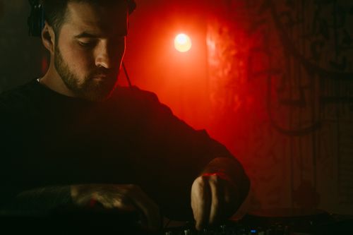 Free DJ mixing electronic music at a nightclub in Lviv, Ukraine with vibrant red lighting. Stock Photo