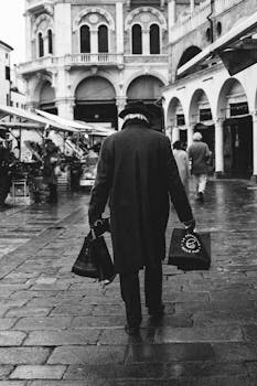 Black and white image of a man walking on wet streets in Padova, Italy.
