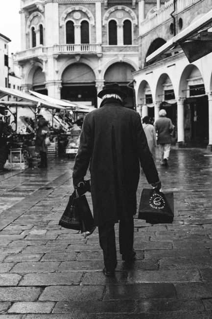 Black and white image of a man walking on wet streets in Padova, Italy.