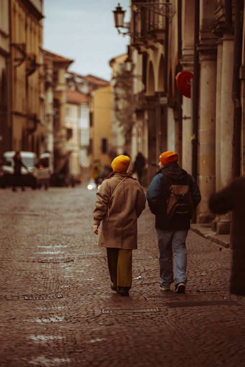 Free Couple in jackets walking on a historic cobblestone street in Padova, Italy. Stock Photo