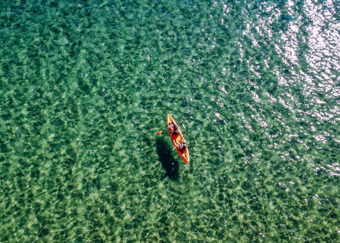 Two people canoeing across a sunlit lake — photo by Daniel Reynaga on Pexels
