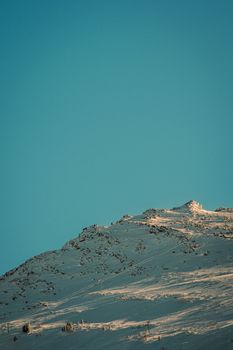 A serene winter landscape featuring a snow-covered mountain slope and ski lift under a clear blue sky.