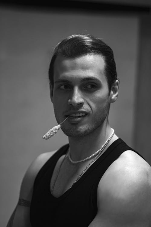 A man in a tank top smoking a cigarette