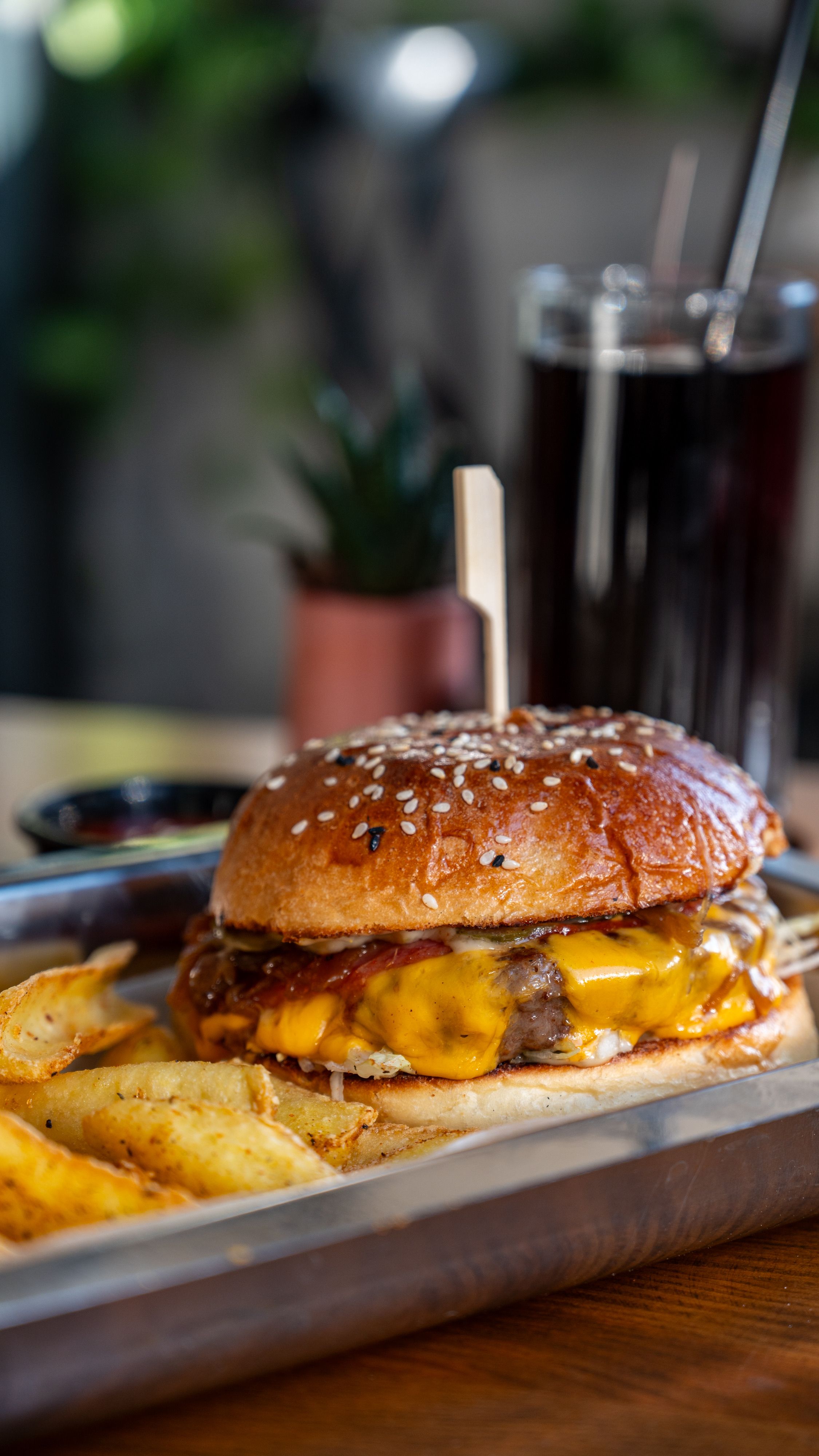 Juicy cheeseburger on a tray with crispy fries and a cold drink, perfect for lunch.