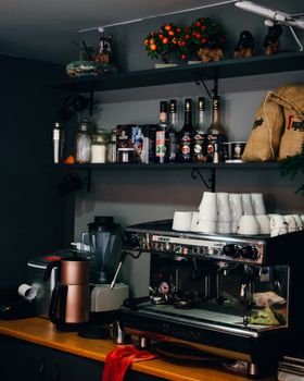 Coffee shop counter featuring an espresso machine, cups, and coffee bags in a cozy setting.