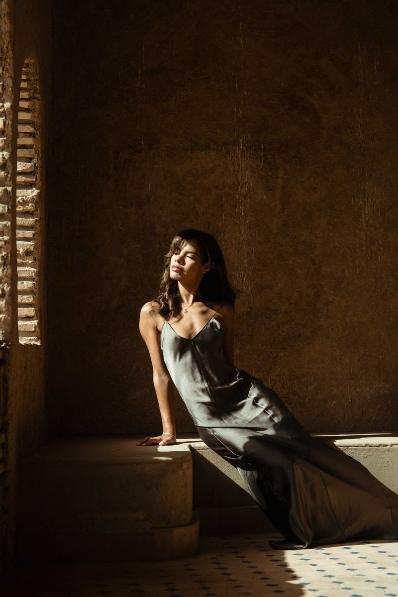Woman in silk dress sitting elegantly, romantic date night outfit