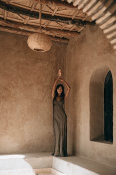 Stylish woman in a long dress poses gracefully indoors in Marrakesh, Morocco.