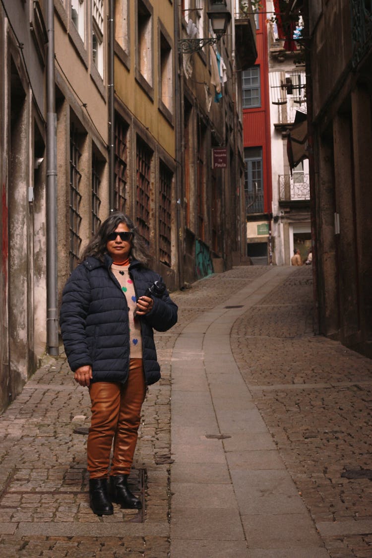 Woman In Jacket And Sunglasses In Alley In City