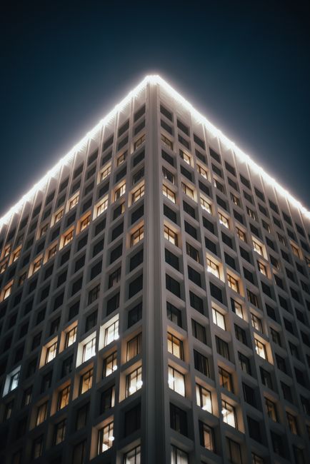 An upward view of an illuminated skyscraper against a night sky, showcasing urban architecture.