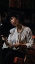 Woman in White Shirt Sitting and Reading Book