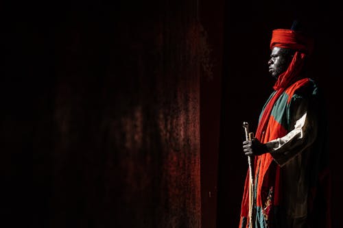 A man in traditional clothing stands in the dark