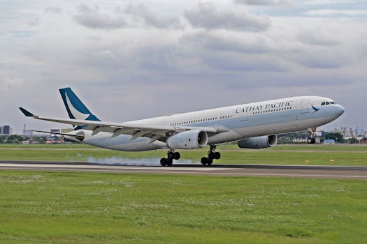 Cathay Pacific aircraft landing on a runway with cityscape background.
