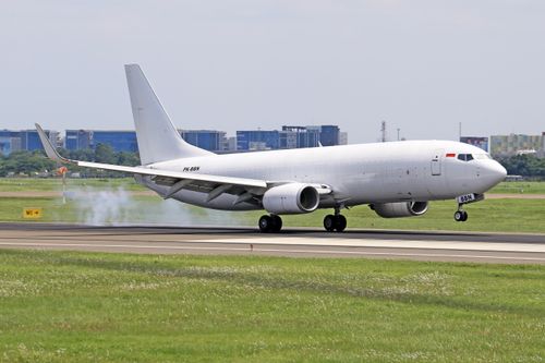 Free A white airplane landing on a runway with visible tire smoke, captured at an airport. Stock Photo