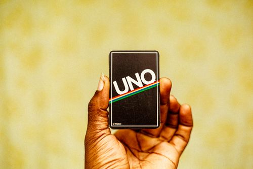 Free A hand holding a classic UNO card with a warm background. Stock Photo