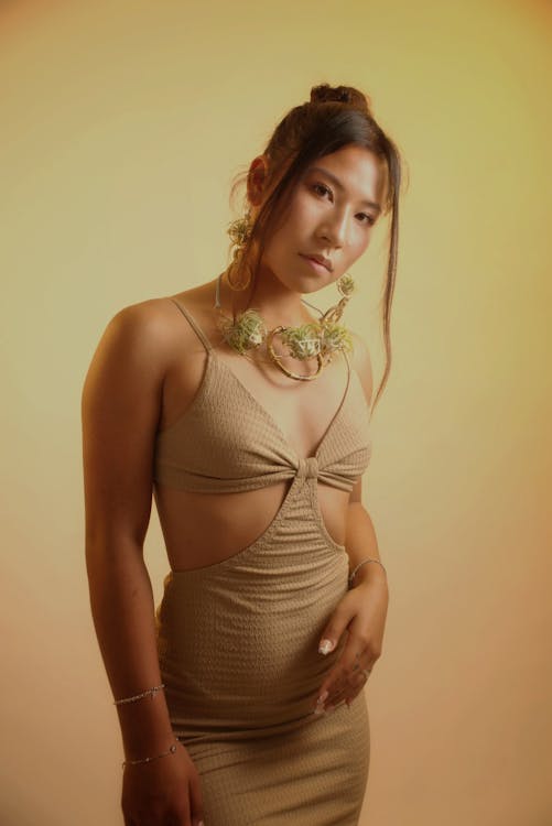 A woman in a tan dress poses for a photo