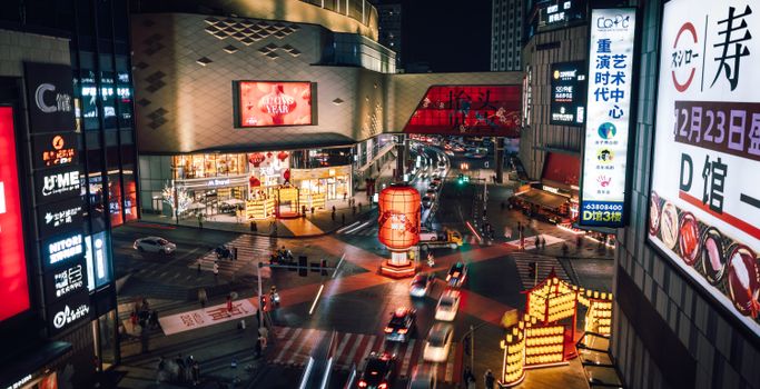 Dynamic city street scene at night with neon lights and traffic in a bustling Asian metropolis.