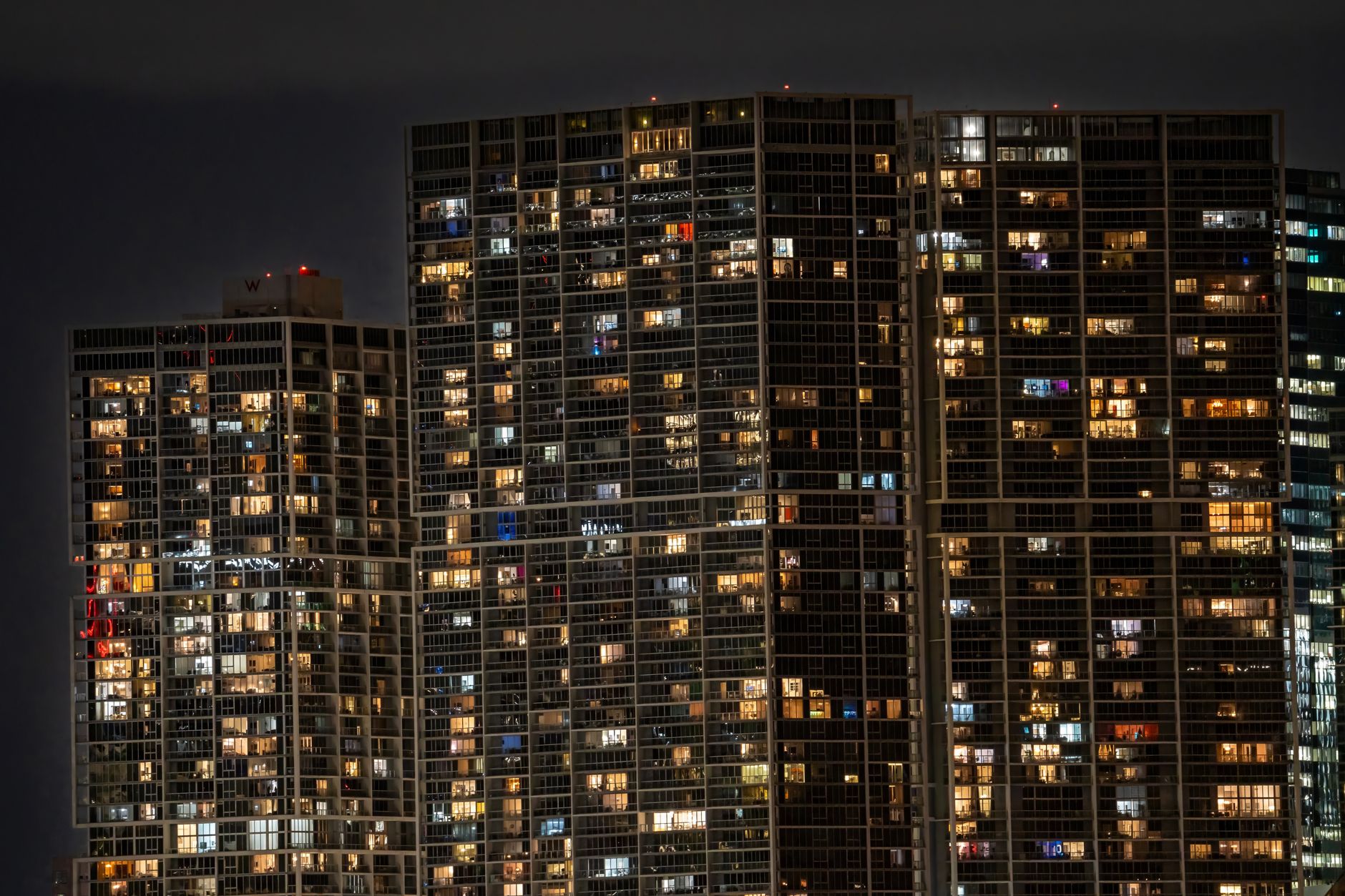 Aerial view of city skyscrapers at night illuminated by lights, creating a vibrant urban scene.