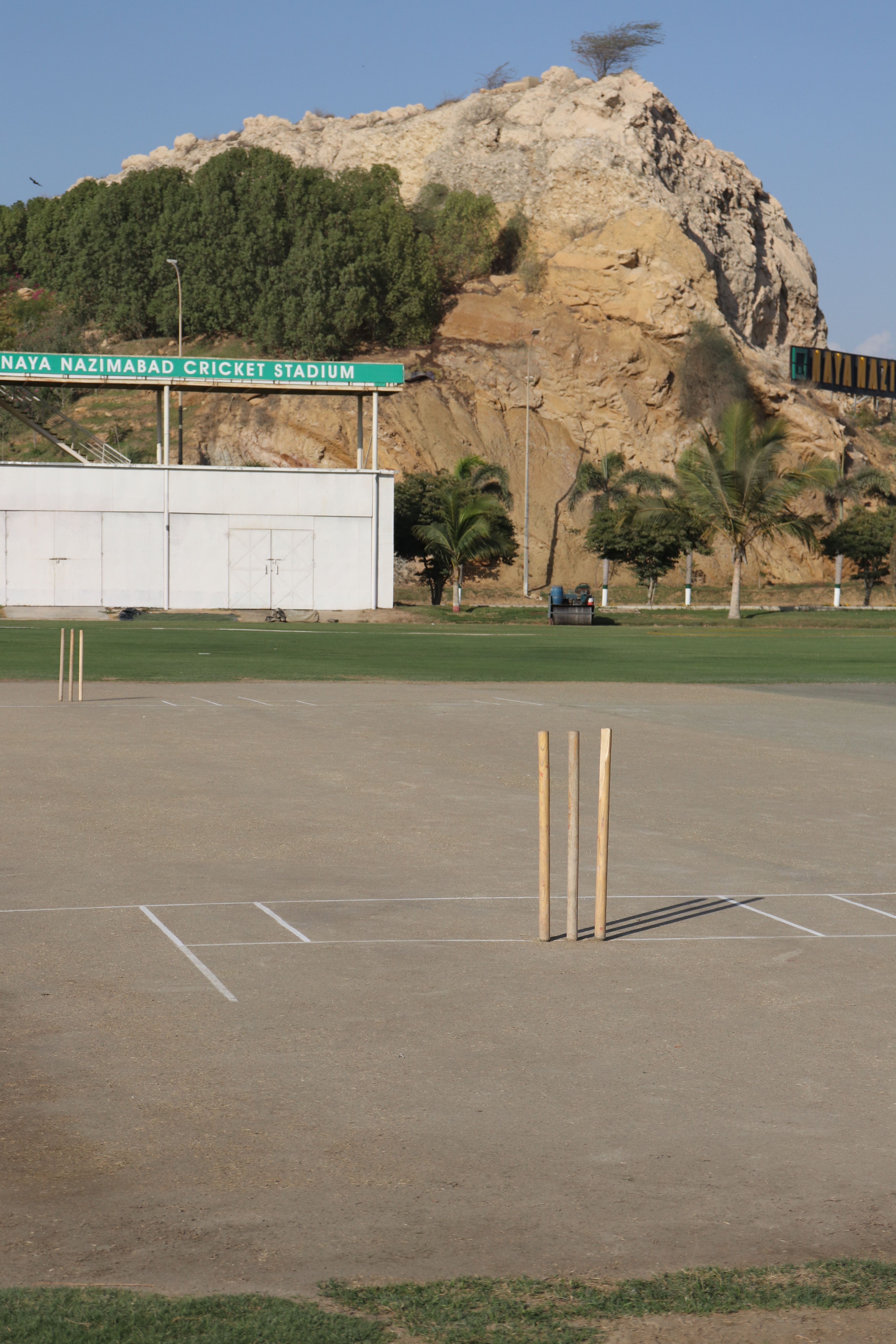 Naya Nazimabad Cricket Stadium with pitch and scenic natural backdrop under a clear sky.