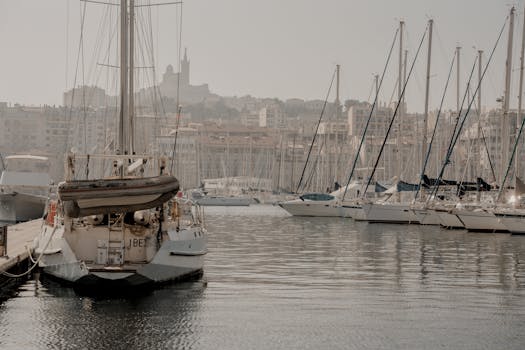 Marseille harbor scene with yachts moored, set against a city backdrop under a summer day.