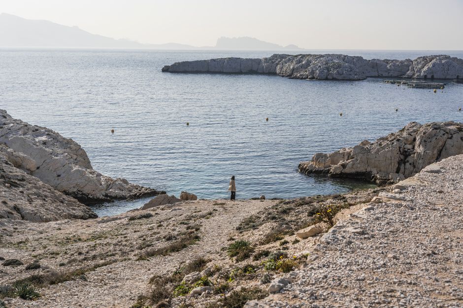 Peaceful seaside scene with rocky cliffs and a solitary figure by the water. Ideal for travel or relaxation themes.