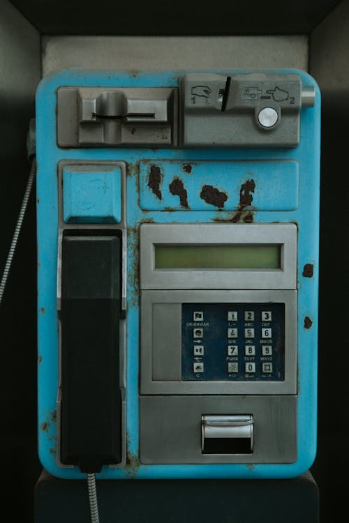 A blue pay phone with a keypad and a key