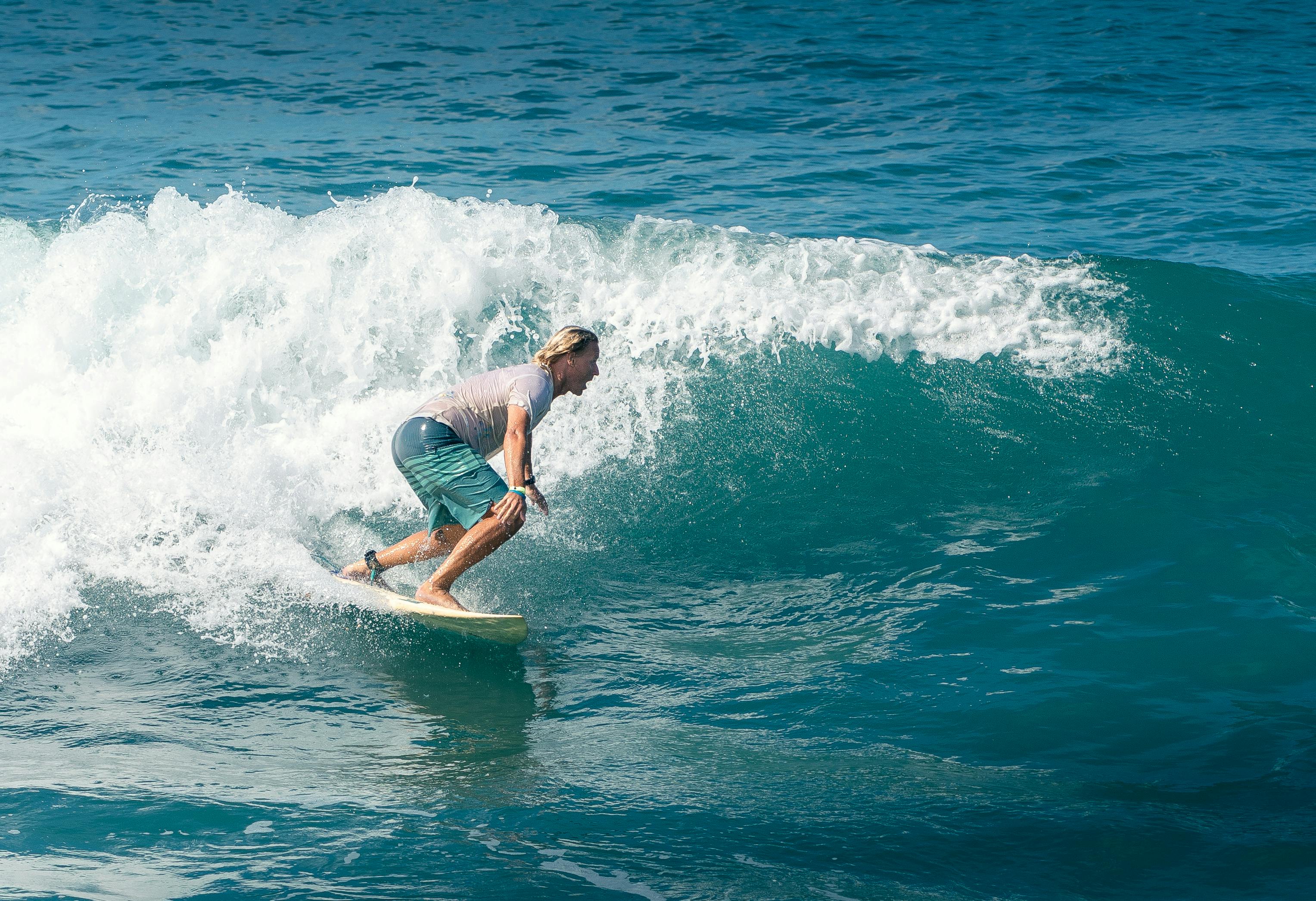 Dynamic shot of a surfer balancing on a wave under the bright sun, capturing the thrill of the ocean.