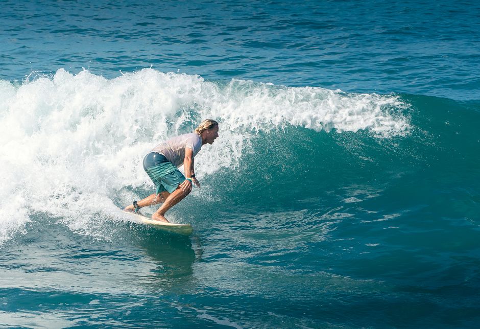 Dynamic shot of a surfer balancing on a wave under the bright sun, capturing the thrill of the ocean.