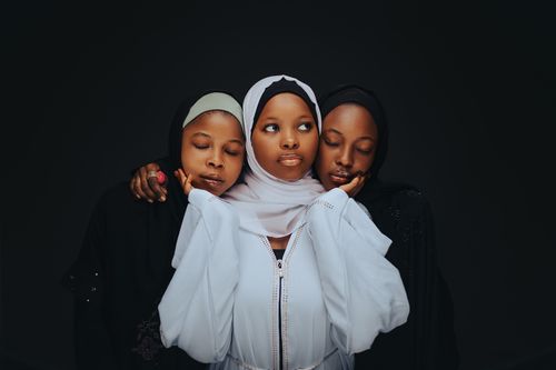 Free Three women in hijabs pose together in a fashion portrait against a black background. Stock Photo