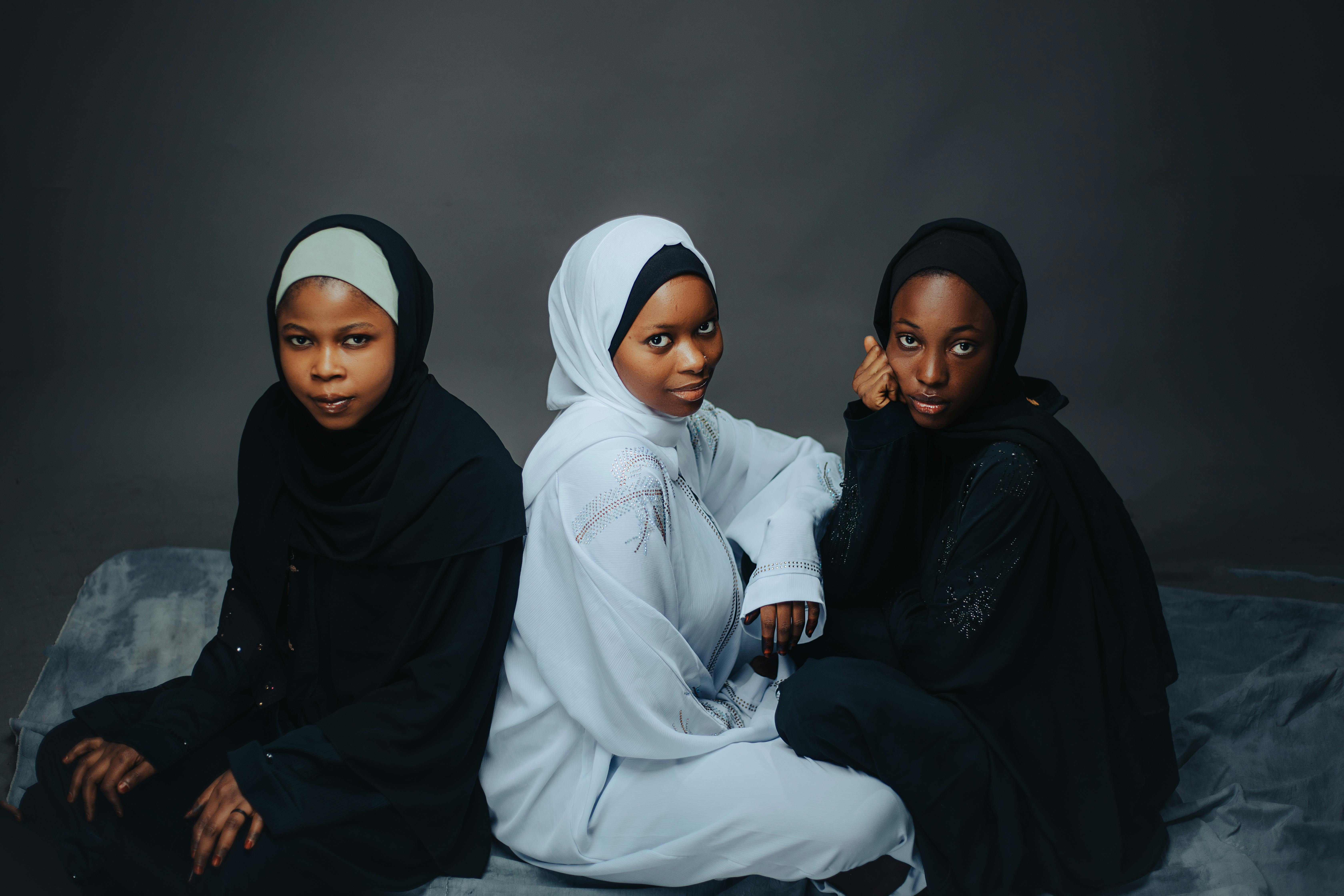 abaya website india - Three women in stylish hijabs seated gracefully, showcasing cultural fashion.