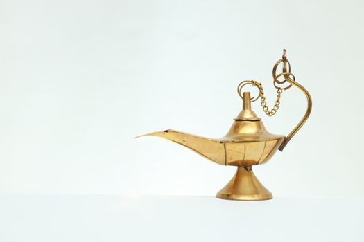 Elegant golden brass genie lamp isolated on a white backdrop, capturing timeless mystique.