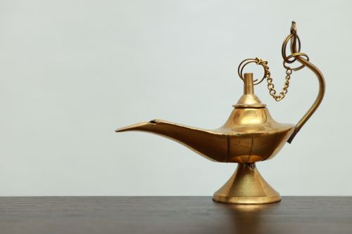 Free A vintage golden genie lamp made of brass placed on a flat surface with a white background, evoking timeless tales. Stock Photo