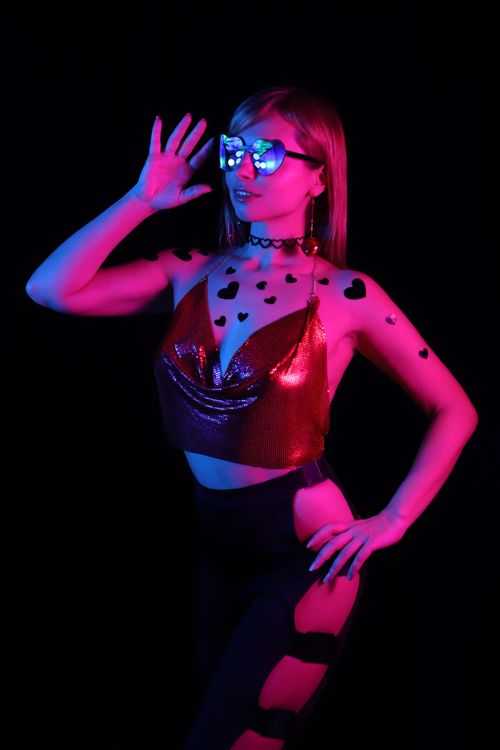 Free Stylish woman posing in neon lights, wearing heart patterns and futuristic glasses. Stock Photo