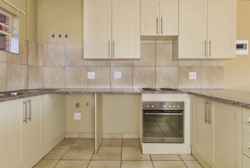 Free A contemporary kitchen interior featuring cream cabinets and tile backsplash with modern appliances. Stock Photo
