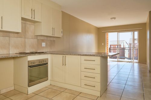 Free Bright modern kitchen with granite countertops and sunlit balcony view, showcasing elegant cabinetry. Stock Photo
