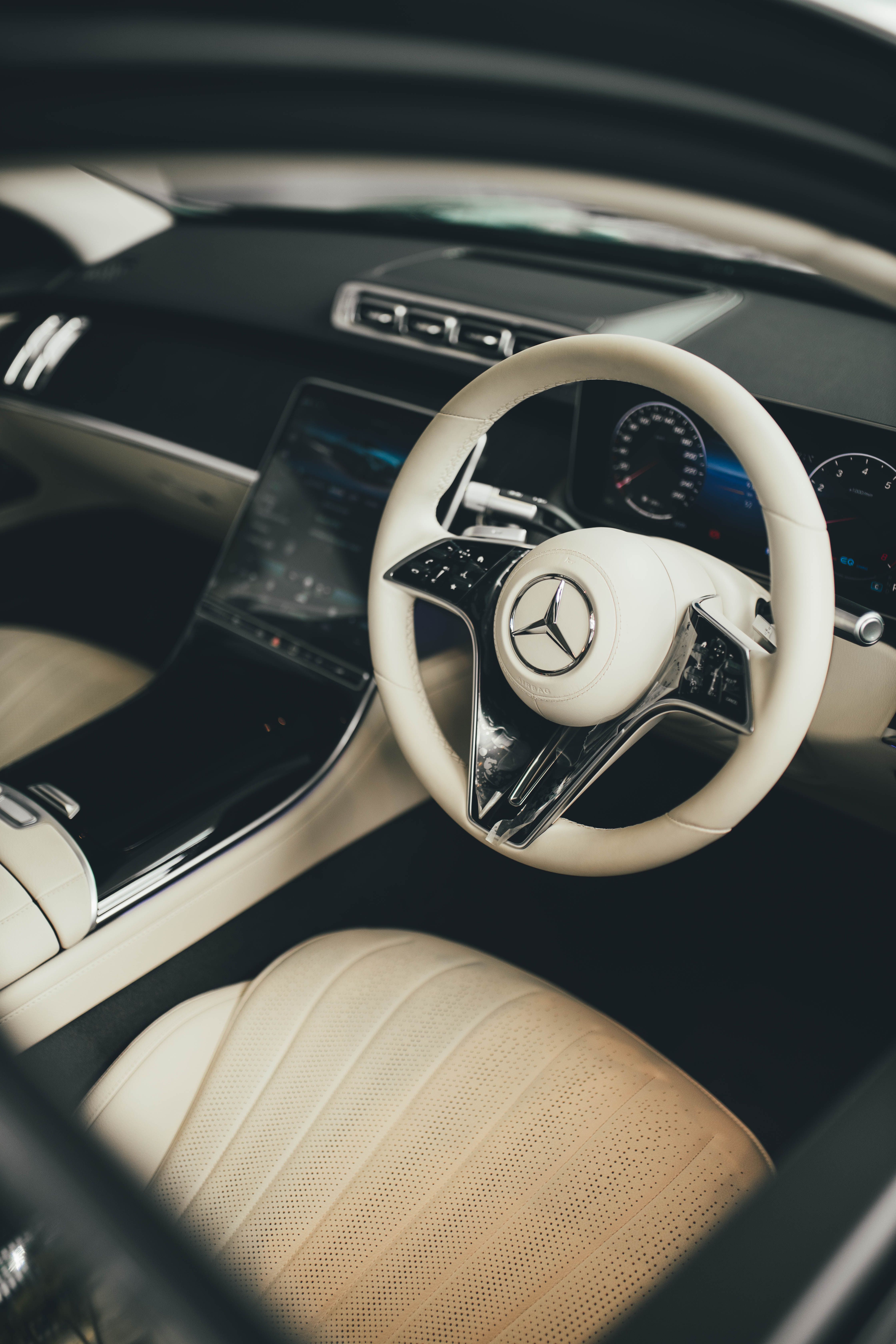 Interior view of a luxurious car showcasing a stylish steering wheel and leather seats.