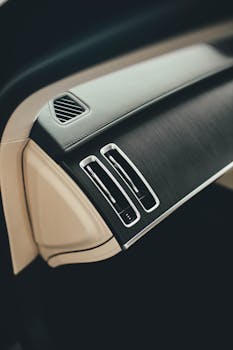 Close-up of a luxury car's modern dashboard with air vents, showcasing minimalist design.
