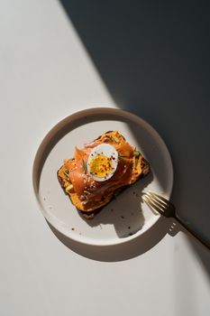 A stylish plate of smoked salmon, egg, and hummus toast in natural light.