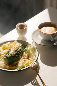 A gourmet breakfast setting featuring avocado salad with coffee and egg for a nutritious start to the day.