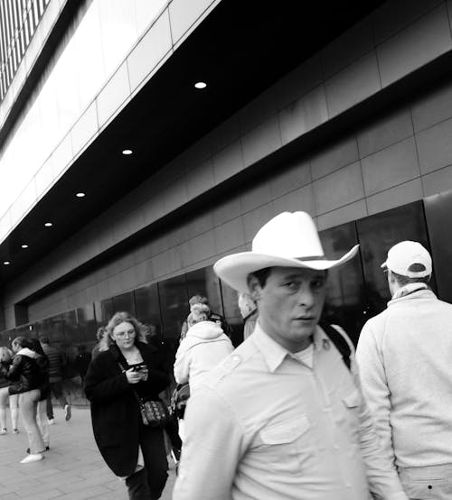 A man in a cowboy hat walking down a sidewalk