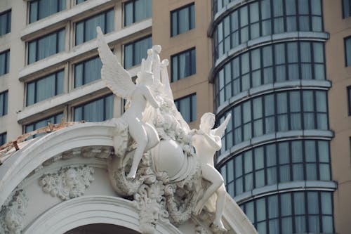 Close-up of a Statue on Top of a Building on the Background of a Modern Facade in City 