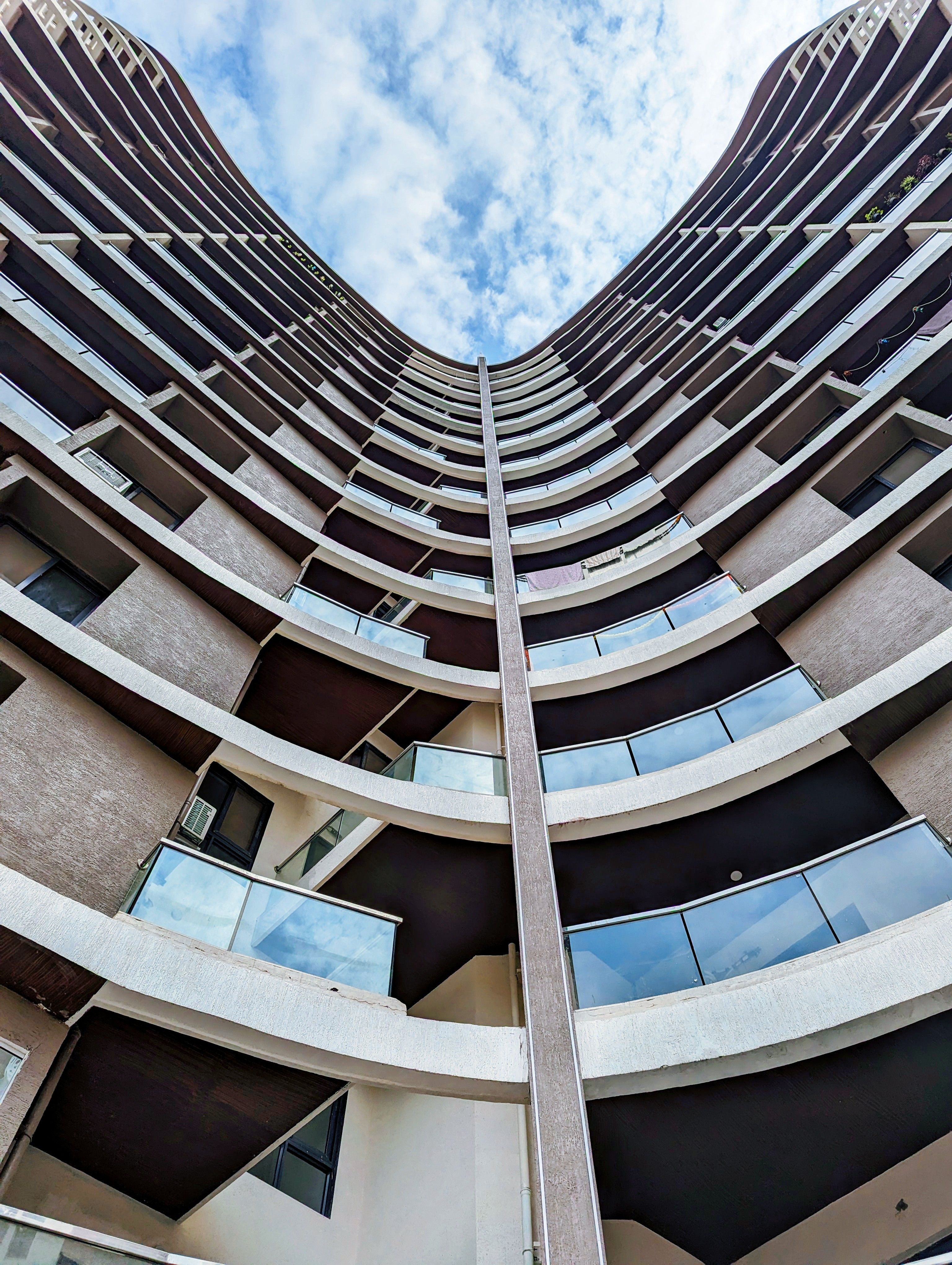 Upward view of a modern, symmetrical high-rise building in Pune, India.