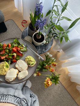 A cozy indoor breakfast setting with fresh salad, avocado toast, and vibrant flowers.