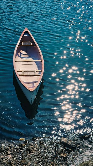Canoe floating on shimmering river water under bright sunlight in Thailand.