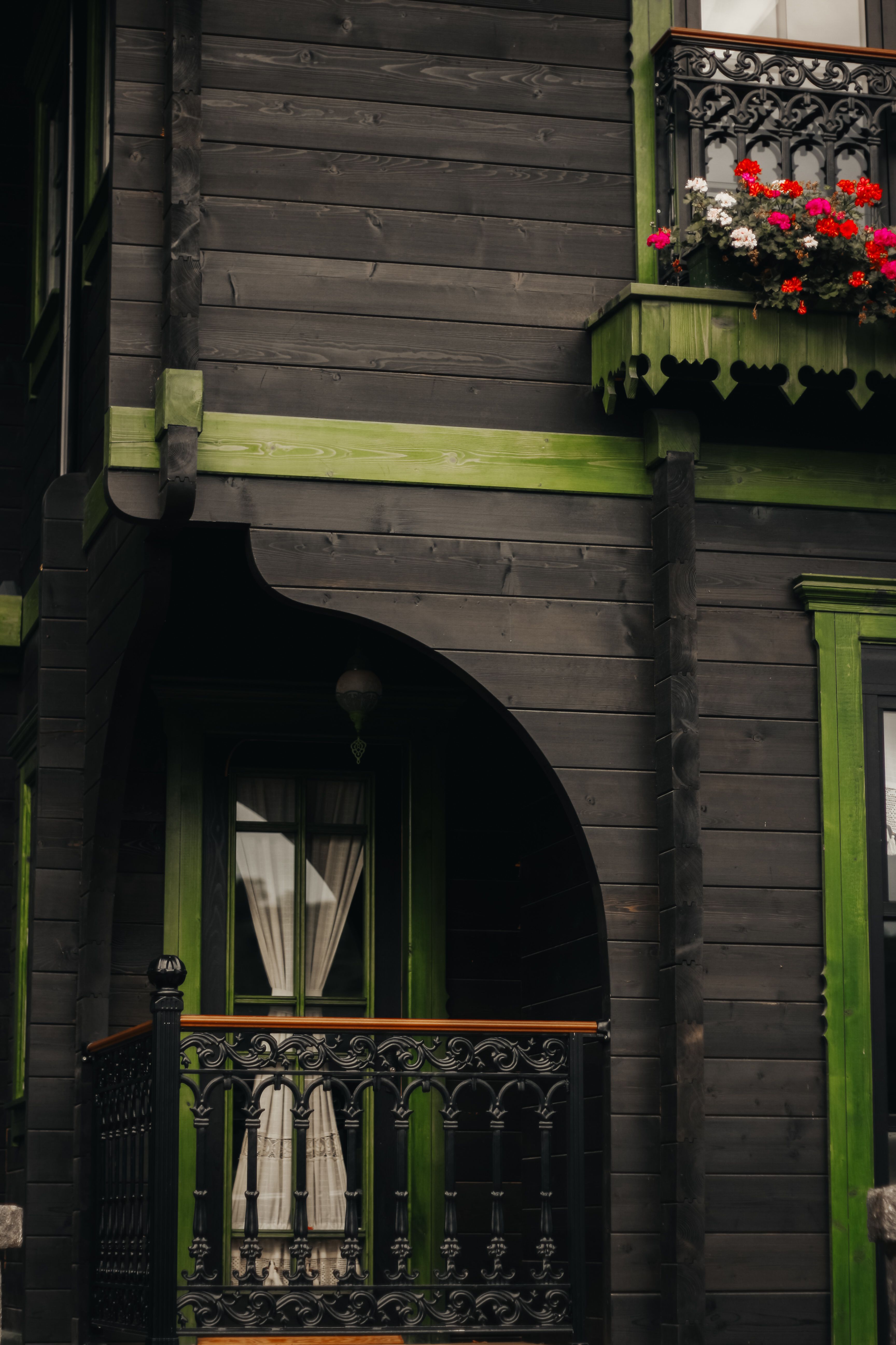 A vintage wooden house facade with ornate iron balcony and floral decoration, offering a cozy rustic charm.